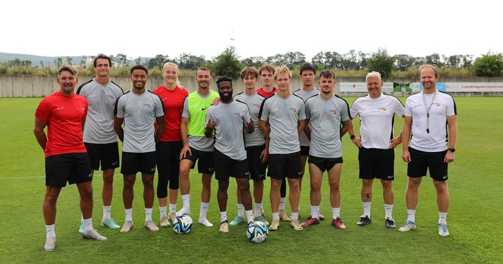 Das letzte Mannschaftsfoto im younion Proficamp 2024! 10 Spieler:innen und drei Trainer versammeln sich am Feld des VIVA Landessportzentrums in Steinbrunn.